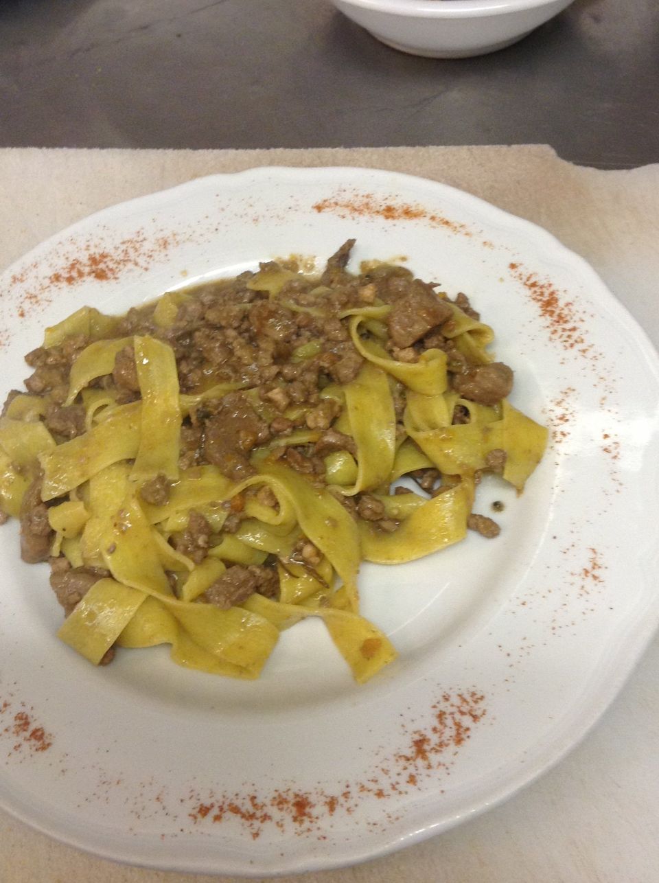 Un piatto bianco con sopra tagliatelle e carne su un tavolo