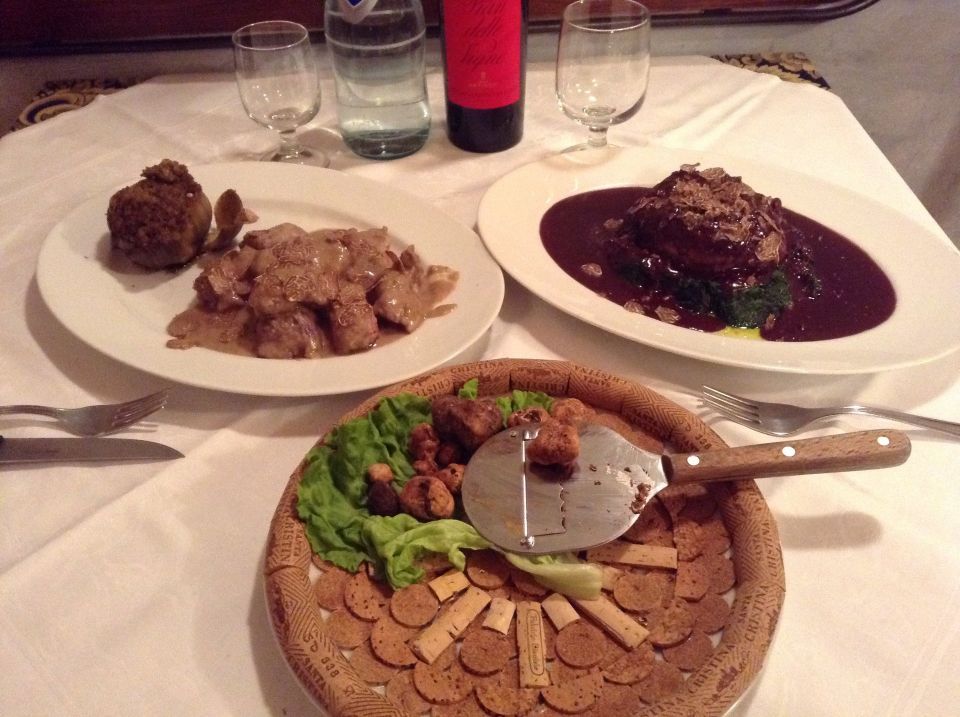 Tre piatti di cibo su un tavolo con una bottiglia di vino