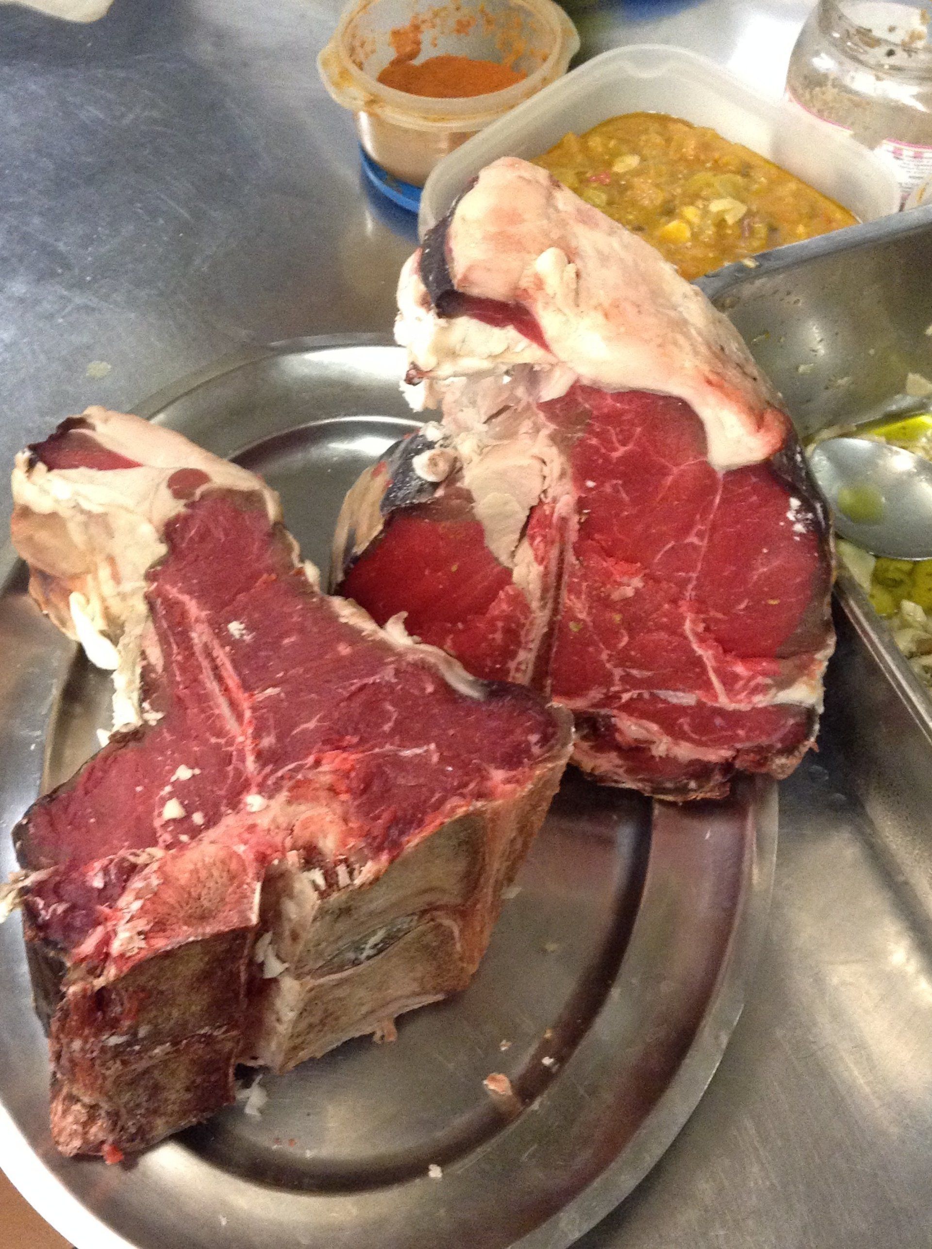 Due grandi pezzi di carne sono appoggiati su un piatto di metallo.