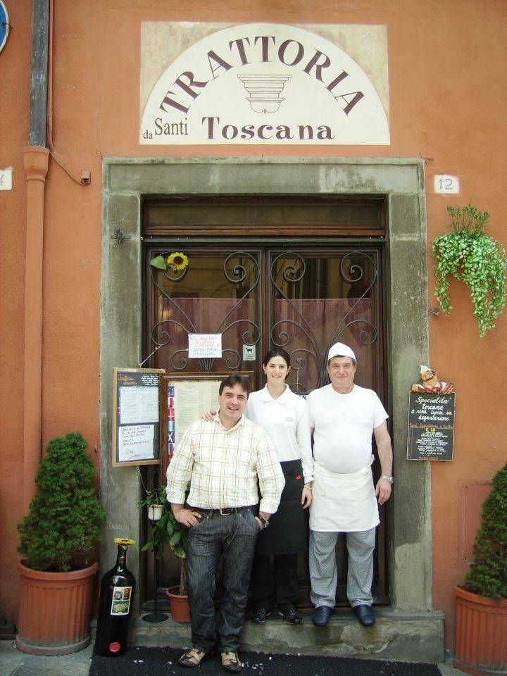 Un gruppo di persone in piedi davanti a un ristorante chiamato trattoria