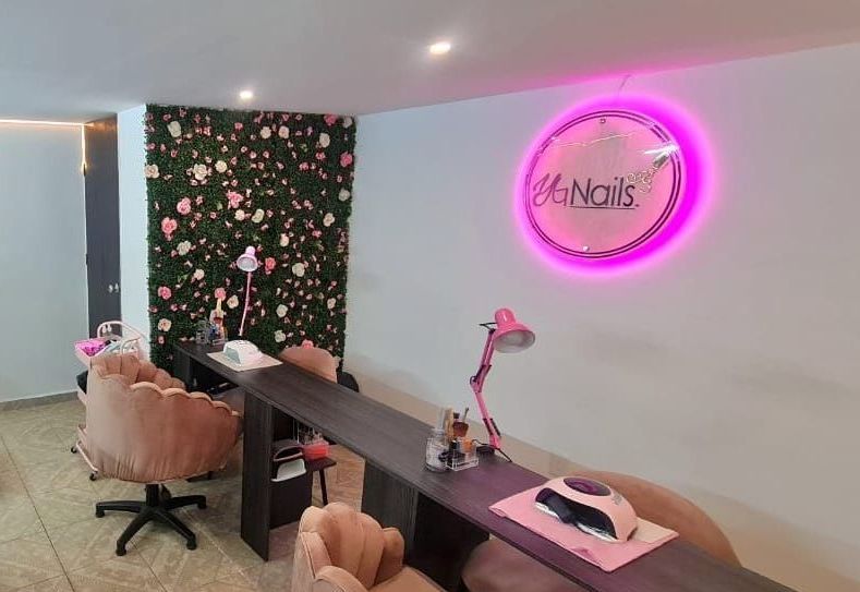 Un salón de uñas con un letrero de neón rosa en la pared.