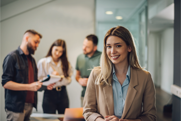 A woman is standing in front of a group of people in an office.
