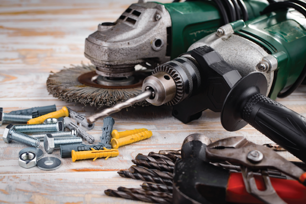 A drill and a grinder are sitting on a wooden table.