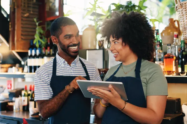 A man and a woman are looking at a tablet in a restaurant.