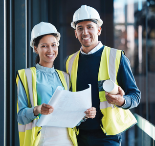 A man and a woman wearing hard hats and safety vests are standing next to each other.