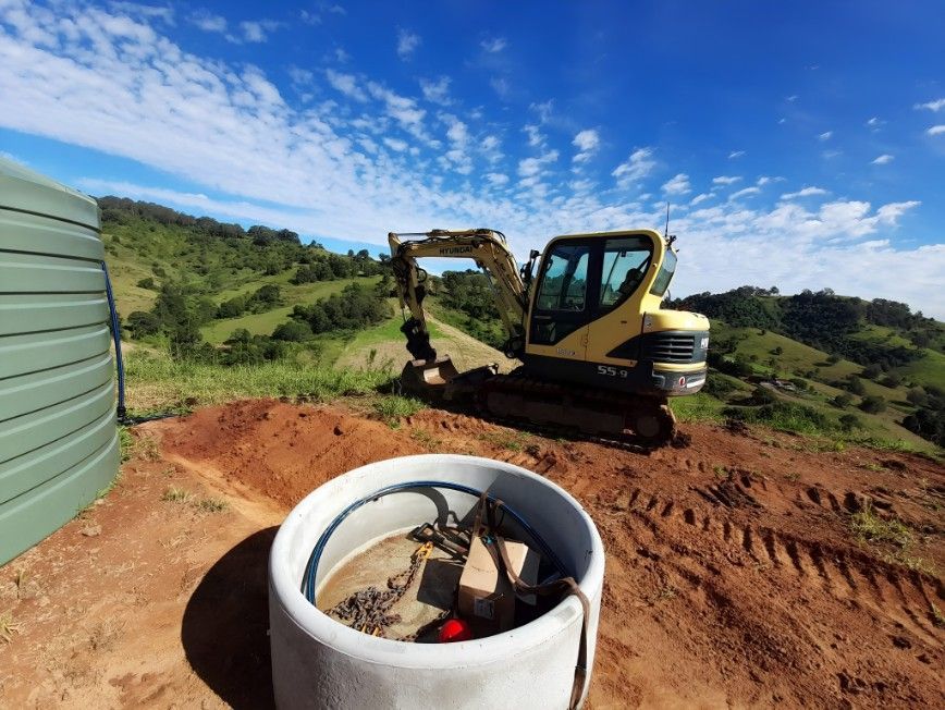 A Yellow Excavator is Digging a Hole in the Dirt — Barrington Coast Contracting in Bulahdelah, NSW