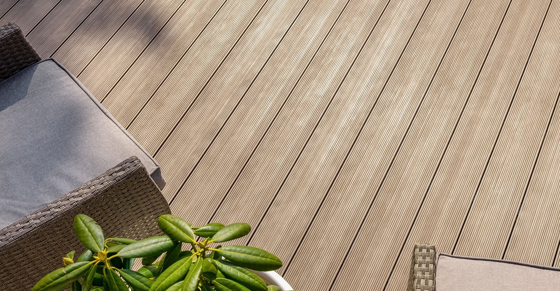 Beige textured composite decking with outdoor furniture and a potted plant.