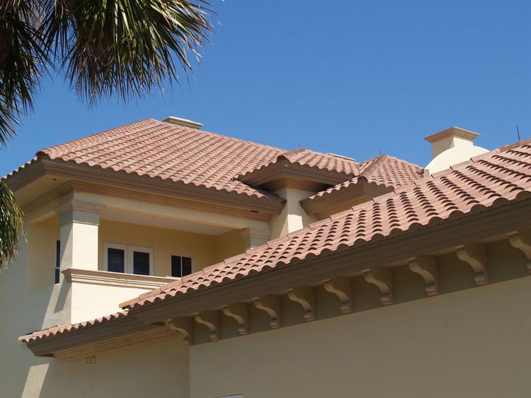 A house with a tiled roof and a palm tree in the background