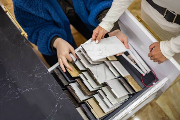 A couple of people are looking at a drawer full of different types of tiles.