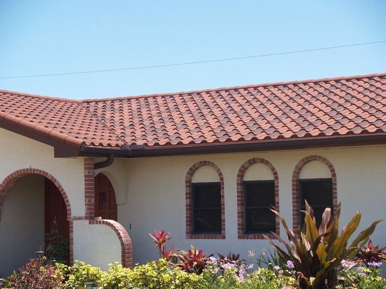A white house with a red tile roof and arched windows