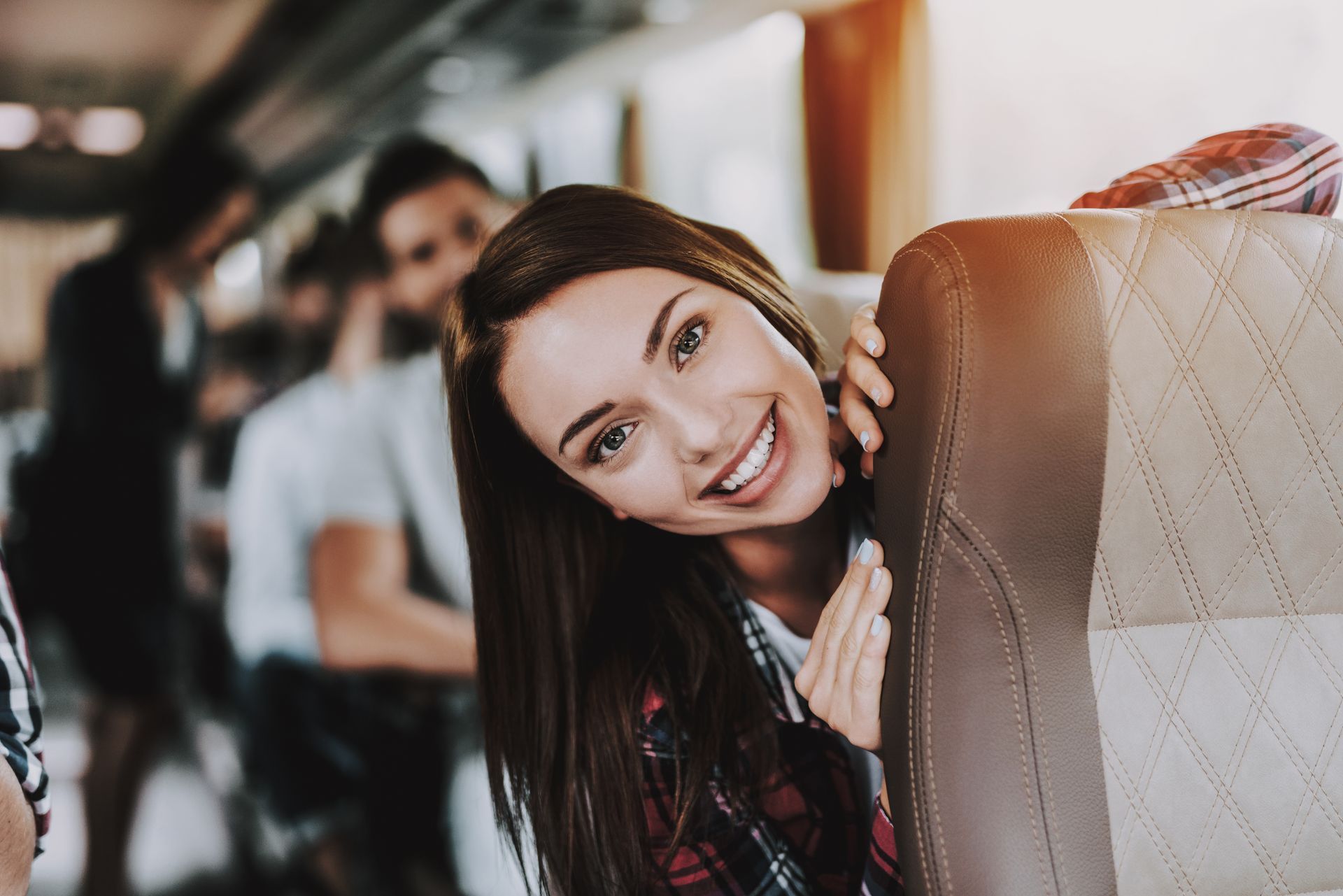 Smiling woman on a bus peeking from behind a seat