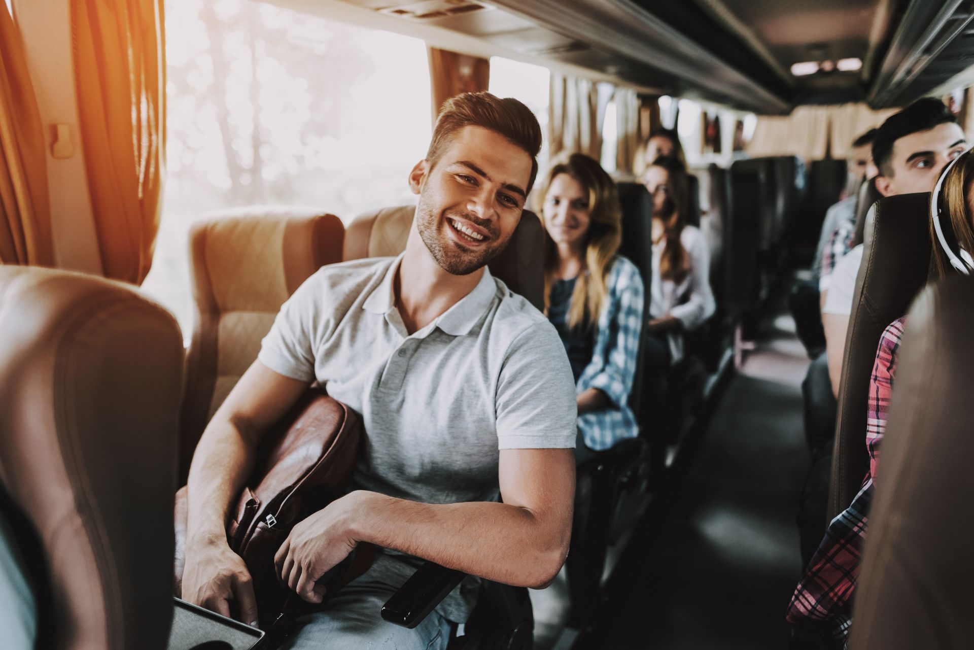 Man smiling on a bus, holding a bag