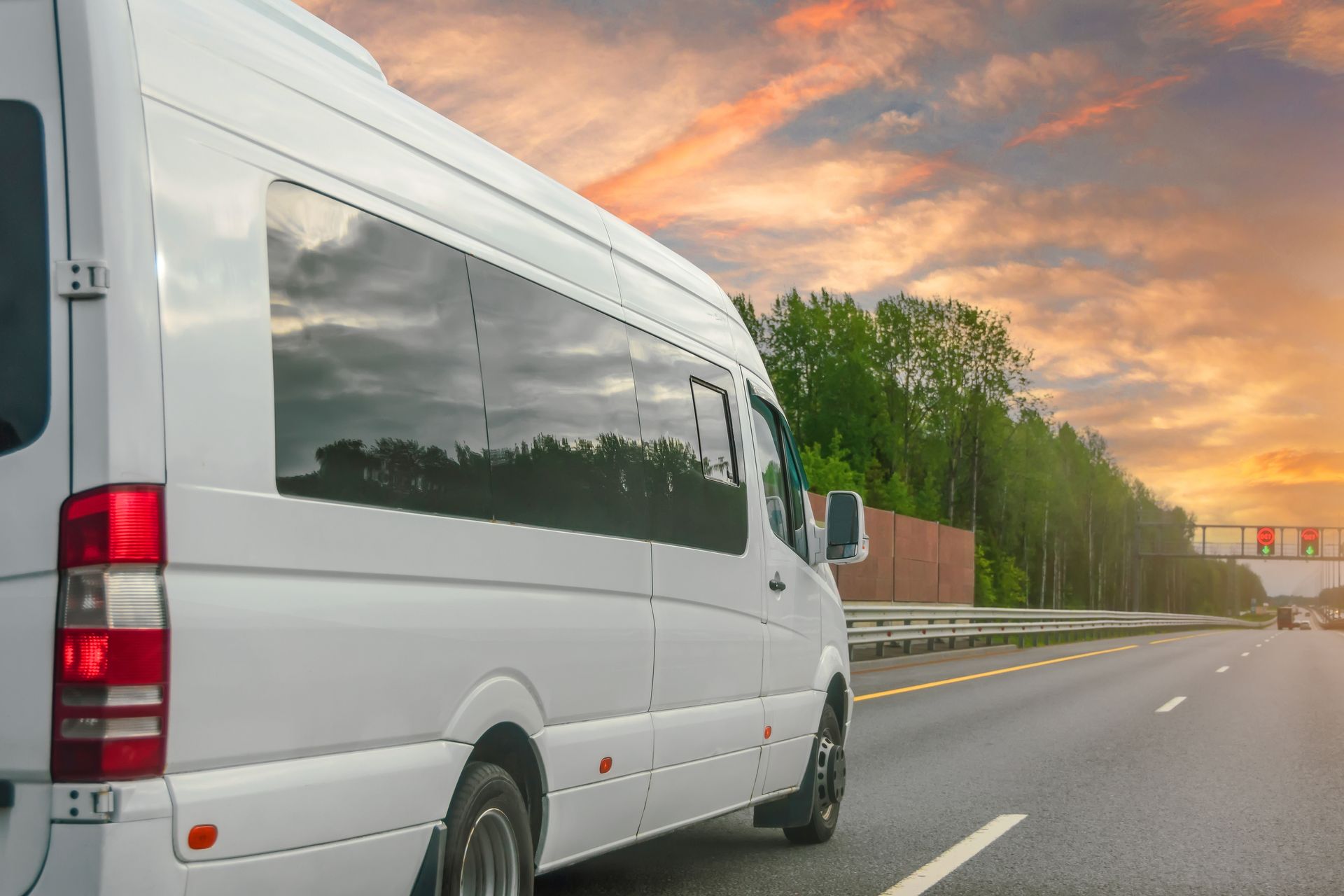 White van driving on a highway at sunset