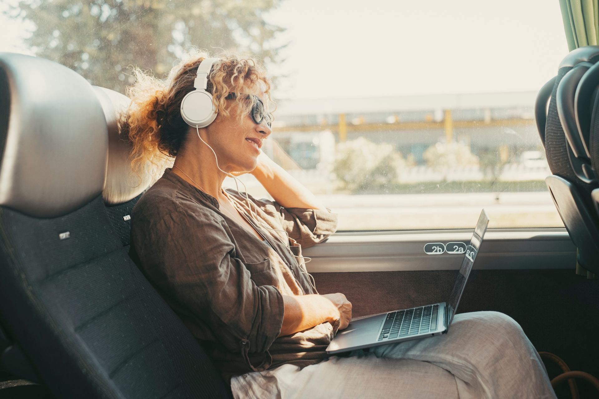 Woman on a bus wearing headphones and sunglasses