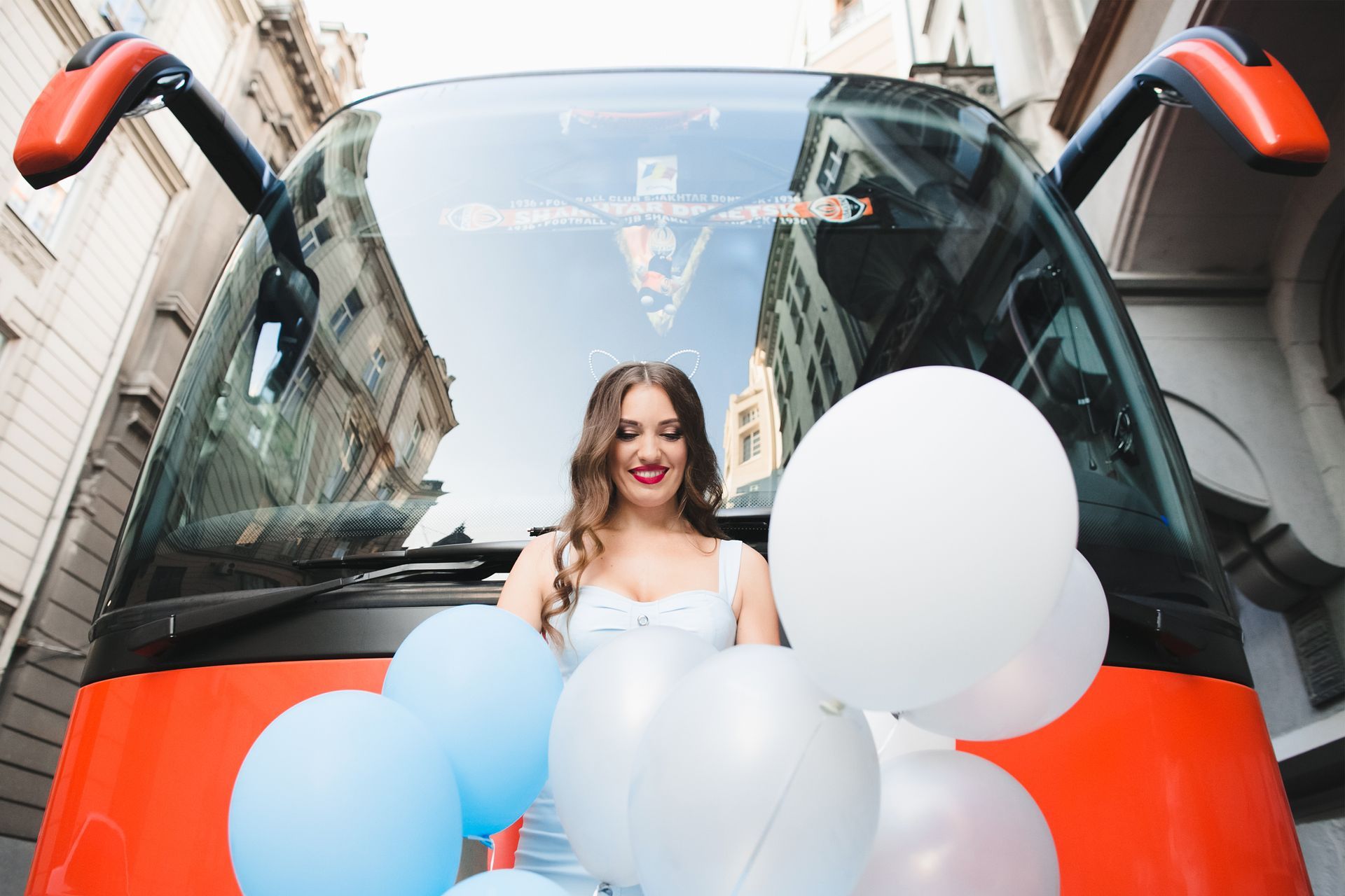 Woman with balloons in front of a red bus