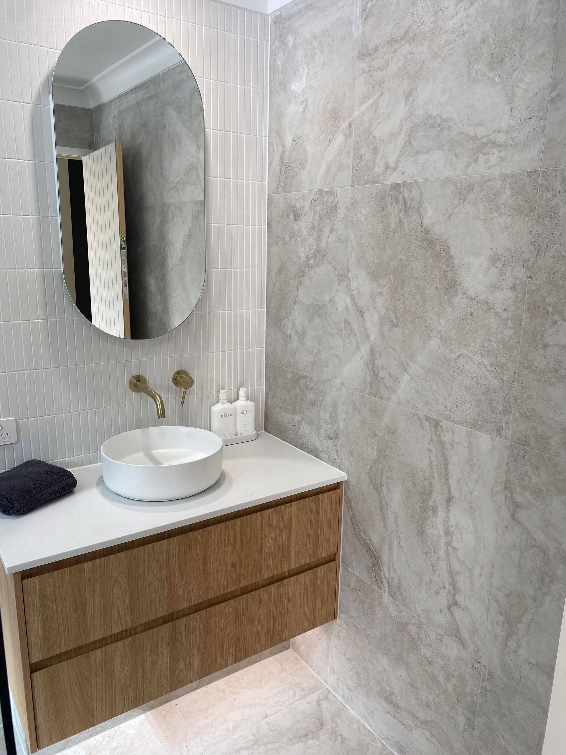 A bathroom with a grey concrete round basin, oval wall mirror  — Holloway Brothers In Tweed Heads, NSW