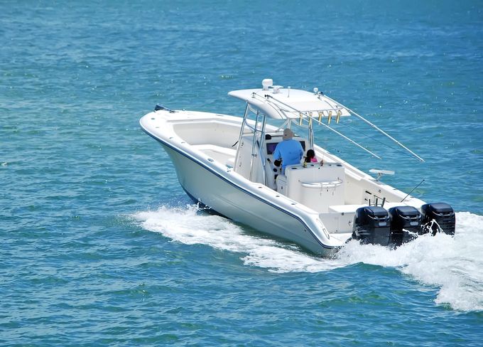 Motoscafo bianco che sfreccia sull'acqua blu con due persone a bordo e motori fuoribordo a poppa