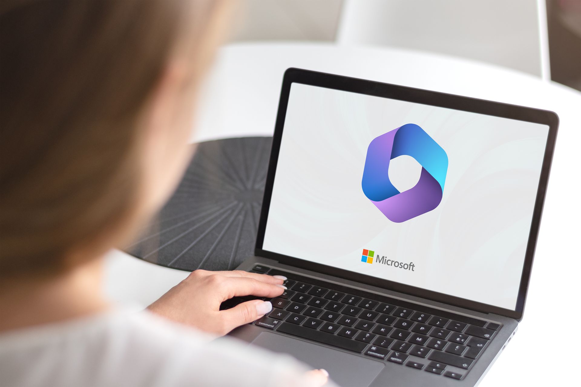 A person is using a laptop computer with a microsoft logo on the screen.
