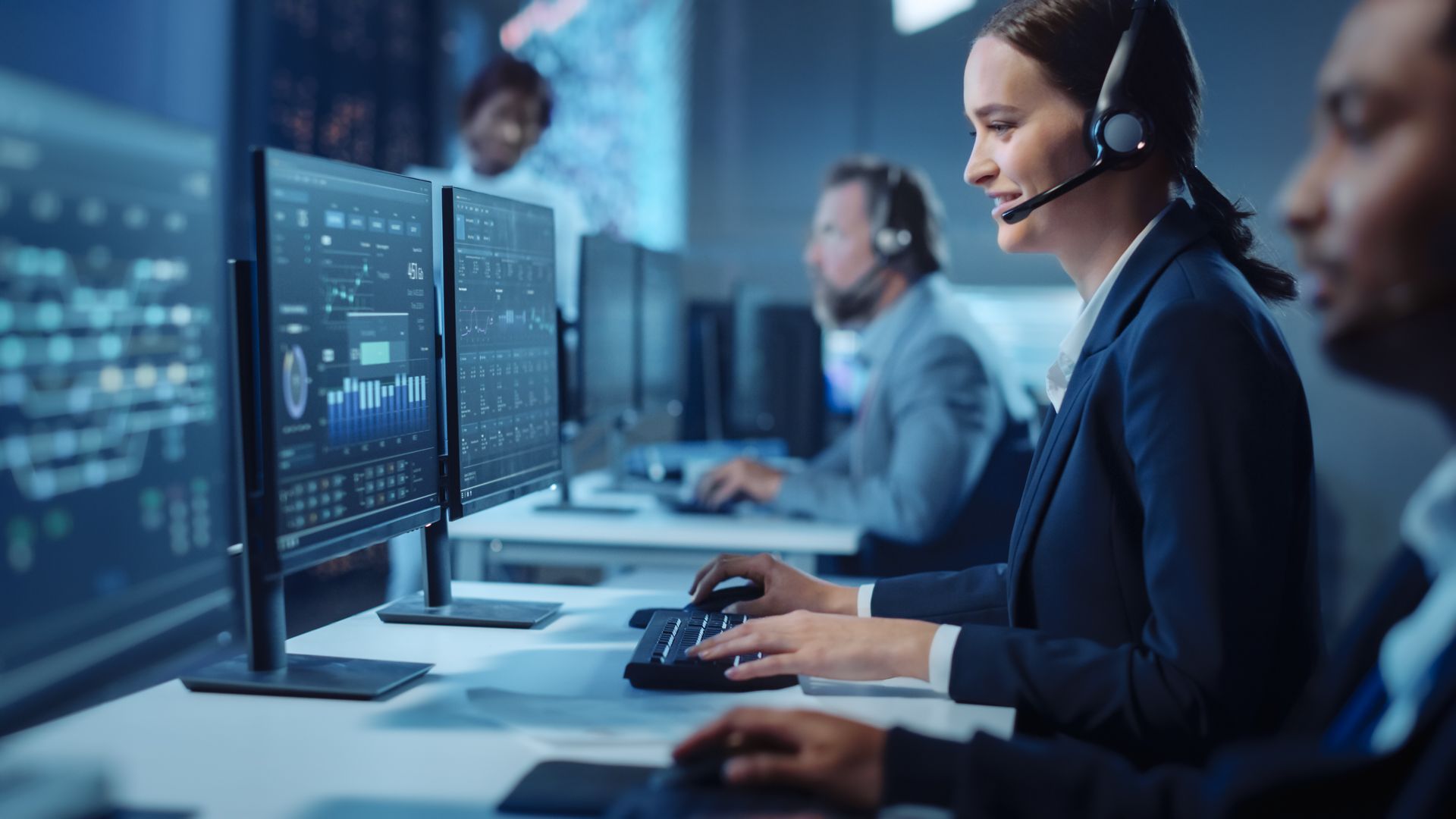 A woman wearing a headset is sitting in front of a computer in a call center.