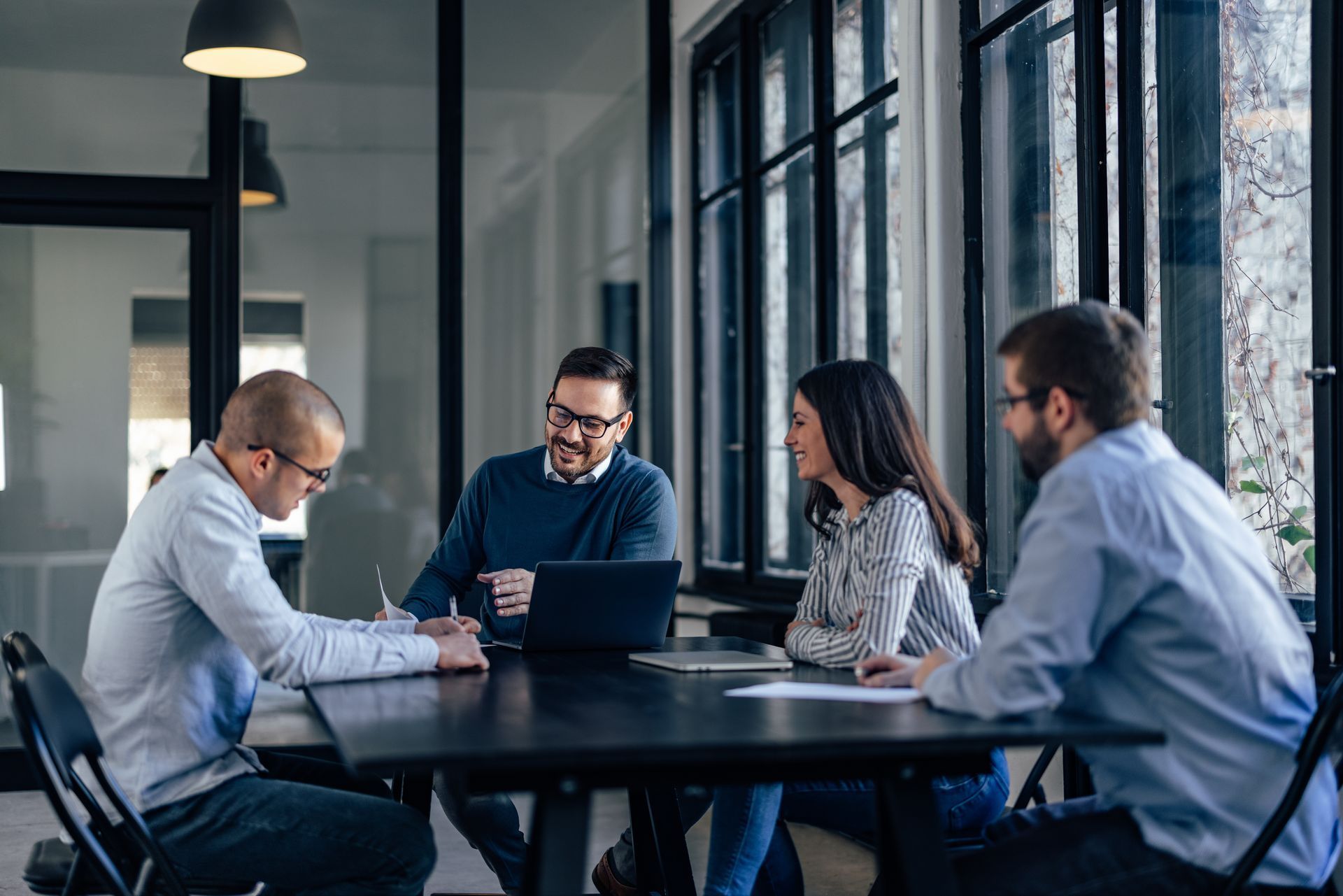 A group of people are sitting around a table with a laptop.