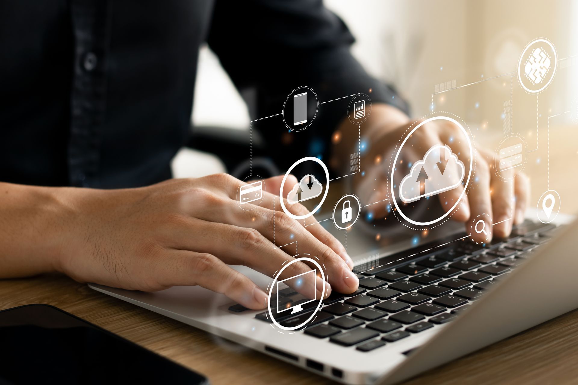 A person is typing on a laptop computer with cloud computing icons coming out of the screen.