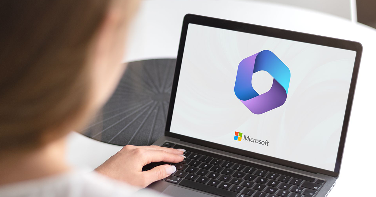 A person is using a laptop computer with a microsoft logo on the screen.