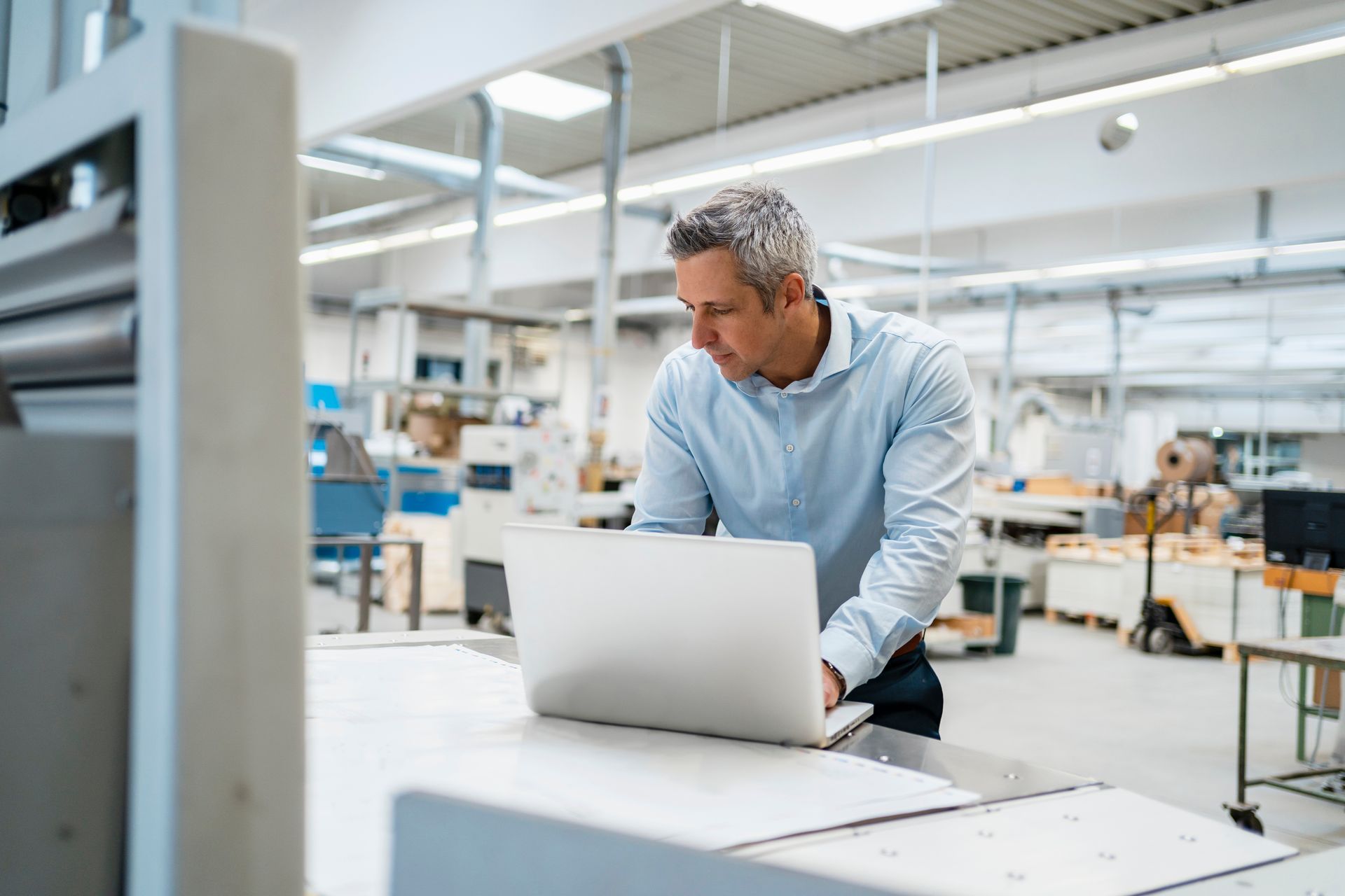 A man is using a laptop computer in a factory.
