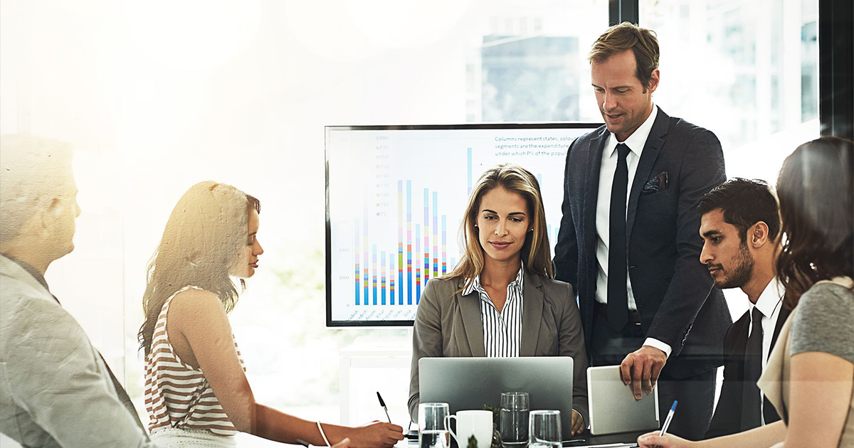 A group of business people are sitting around a conference table having a meeting.