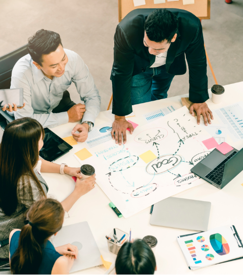 A group of people are sitting around a table with papers and a laptop.