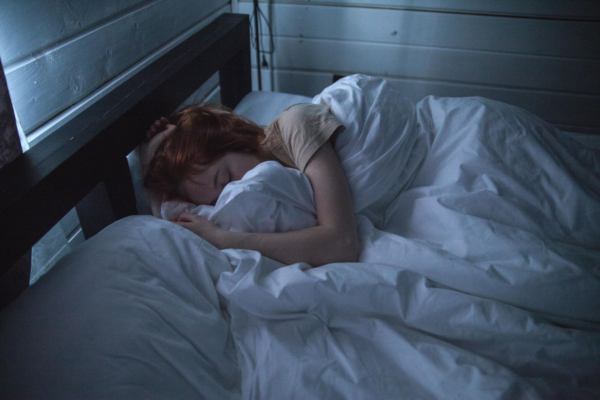 A woman is sleeping in a bed with white sheets.