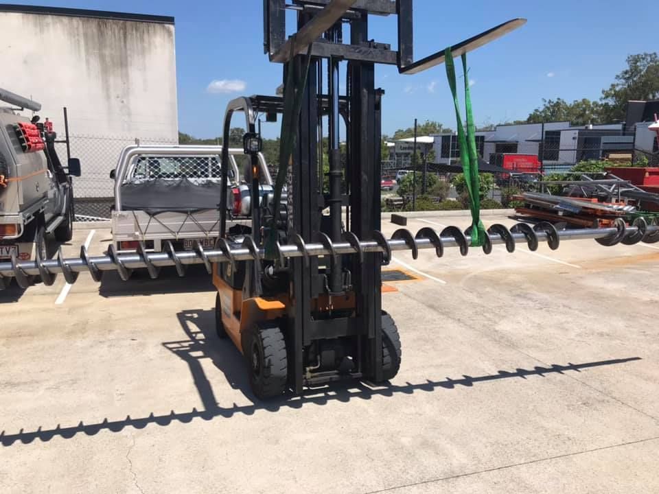 A Forklift Is Carrying A Large Piece Of Metal In A Parking Lot — D.E.M Solutions Pty Ltd In Caboolture, QLD