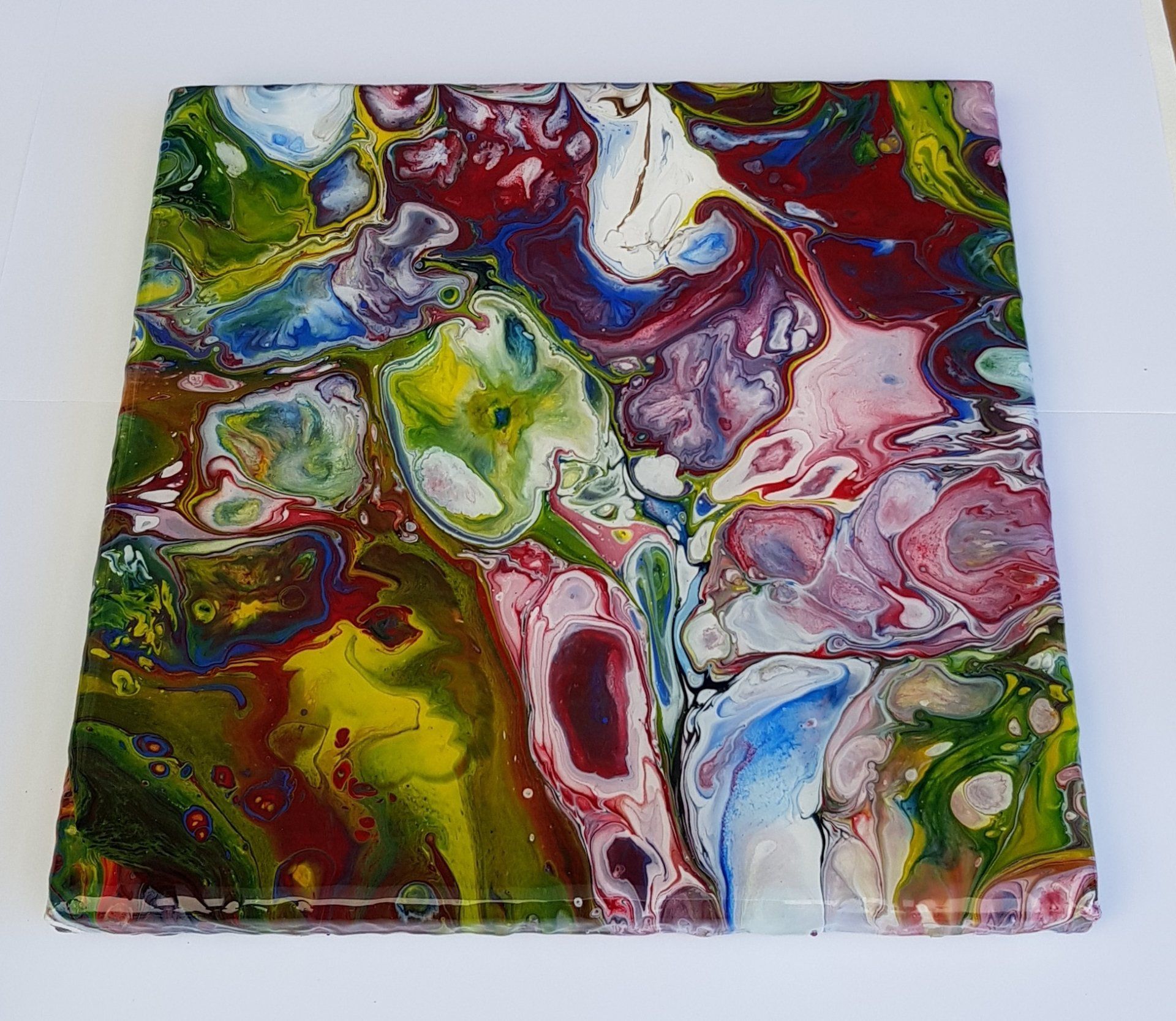 Een kleurrijk schilderij staat op een wit oppervlak