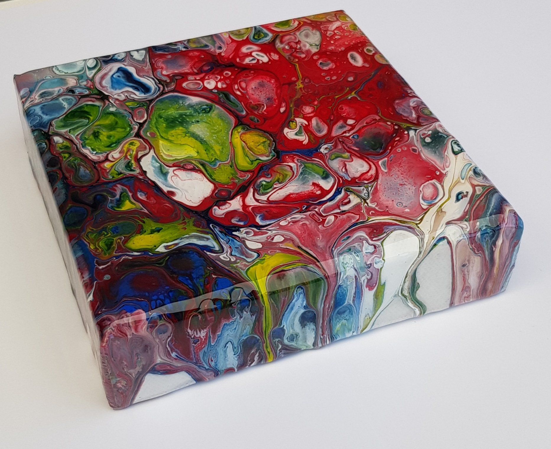 Een kleurrijk schilderij staat op een wit oppervlak