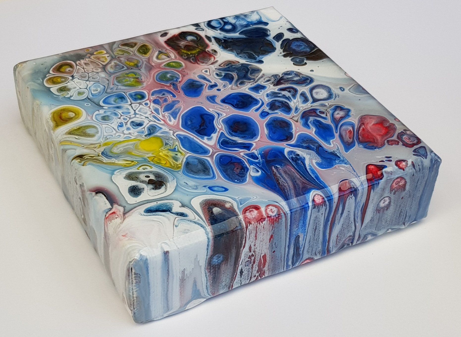 Een kleurrijk schilderij staat op een wit oppervlak.