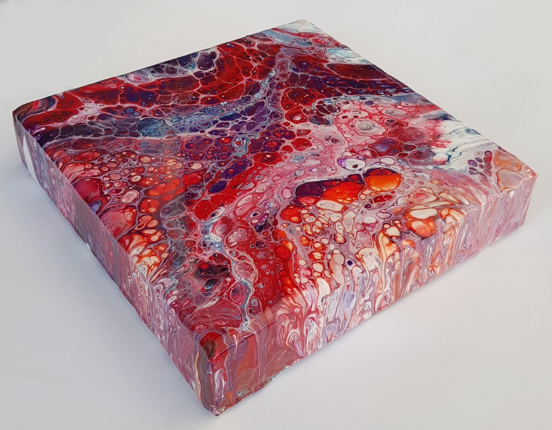 Een schilderij op doek met een rood en paars marmerpatroon