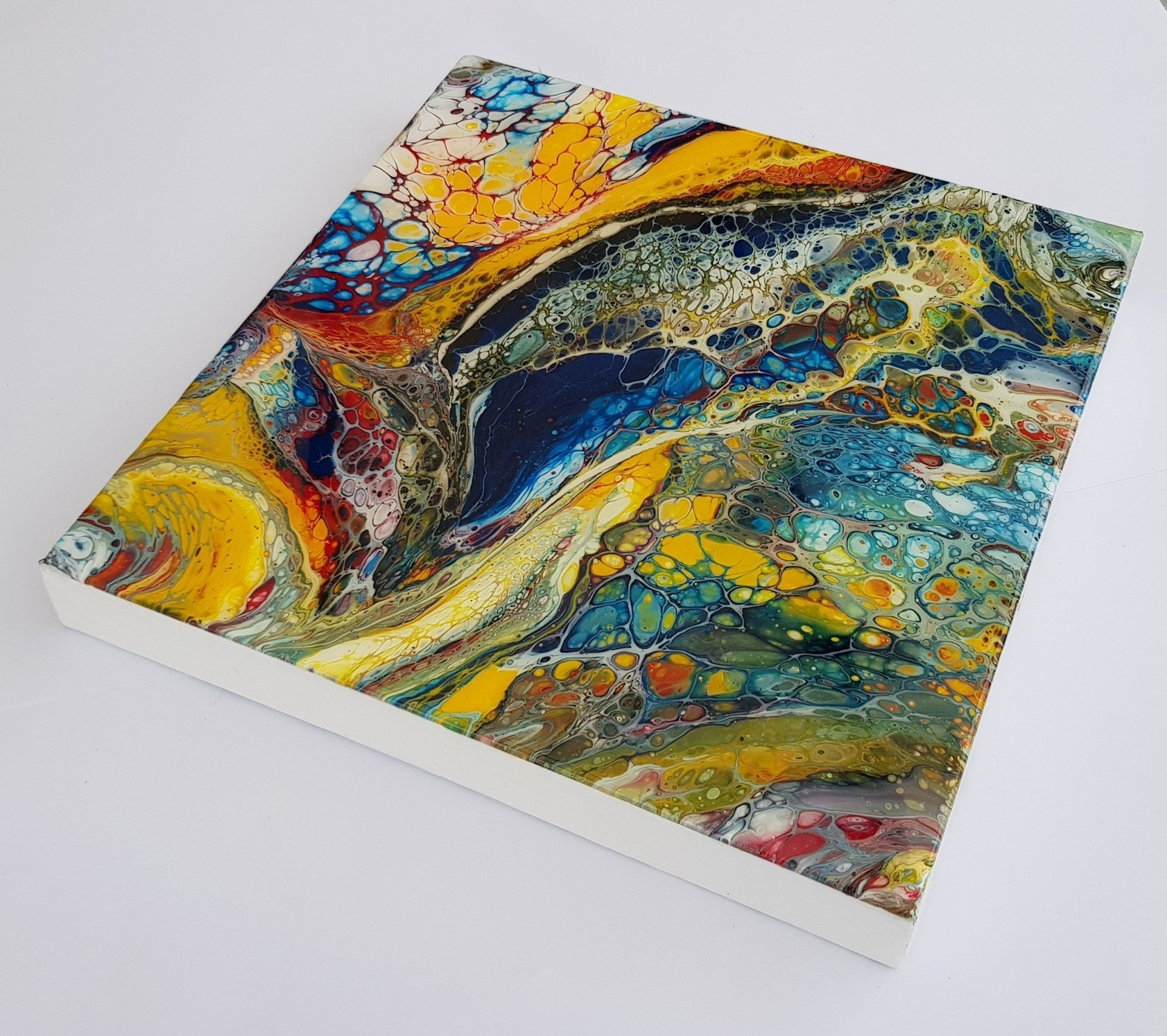 Een kleurrijk schilderij staat op een wit oppervlak