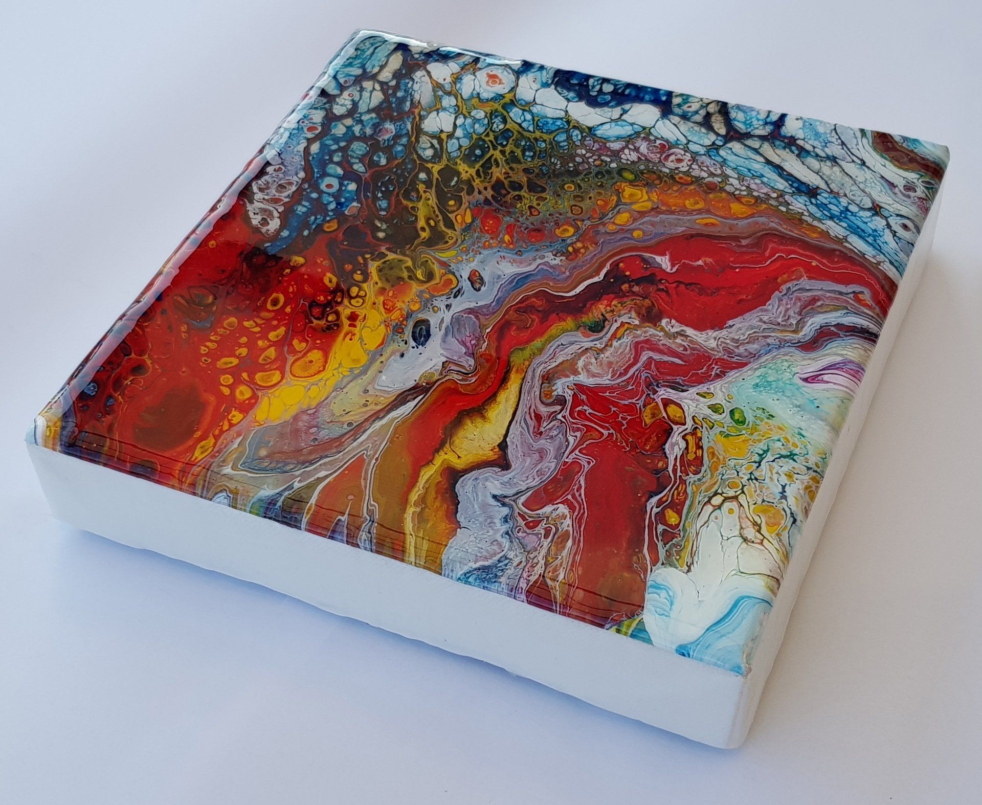 Een kleurrijk schilderij staat op een wit oppervlak