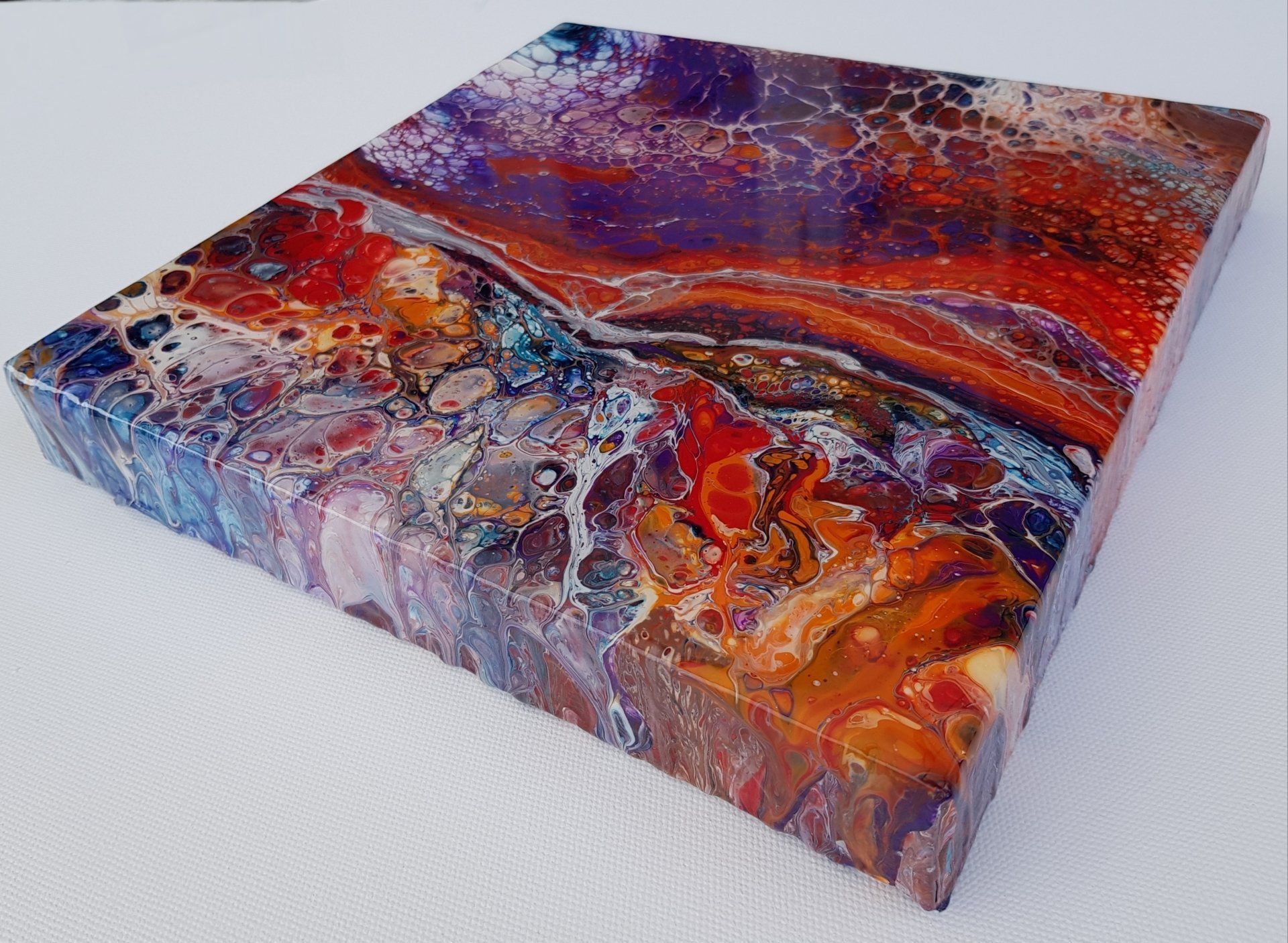 Een kleurrijk schilderij staat op een wit oppervlak.