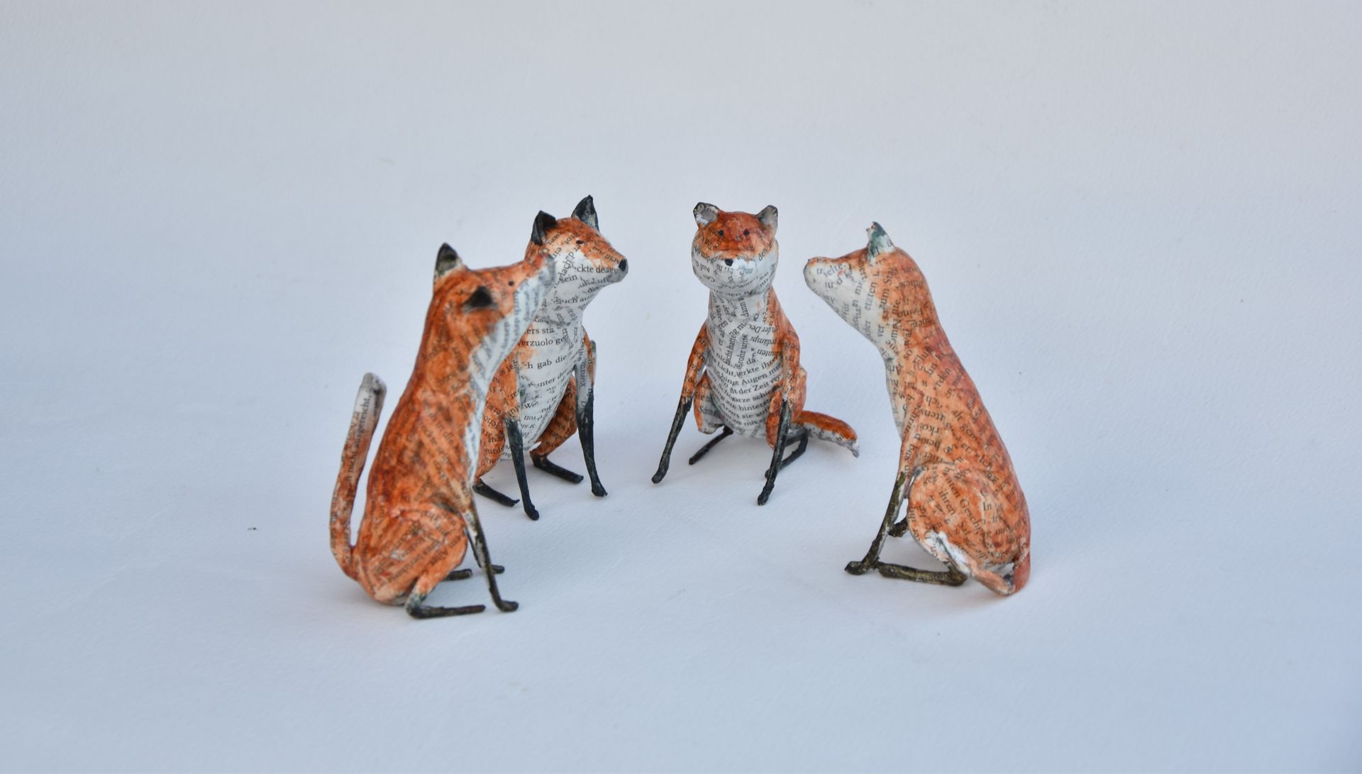 Drie vossenbeeldjes zitten naast elkaar op een wit oppervlak.