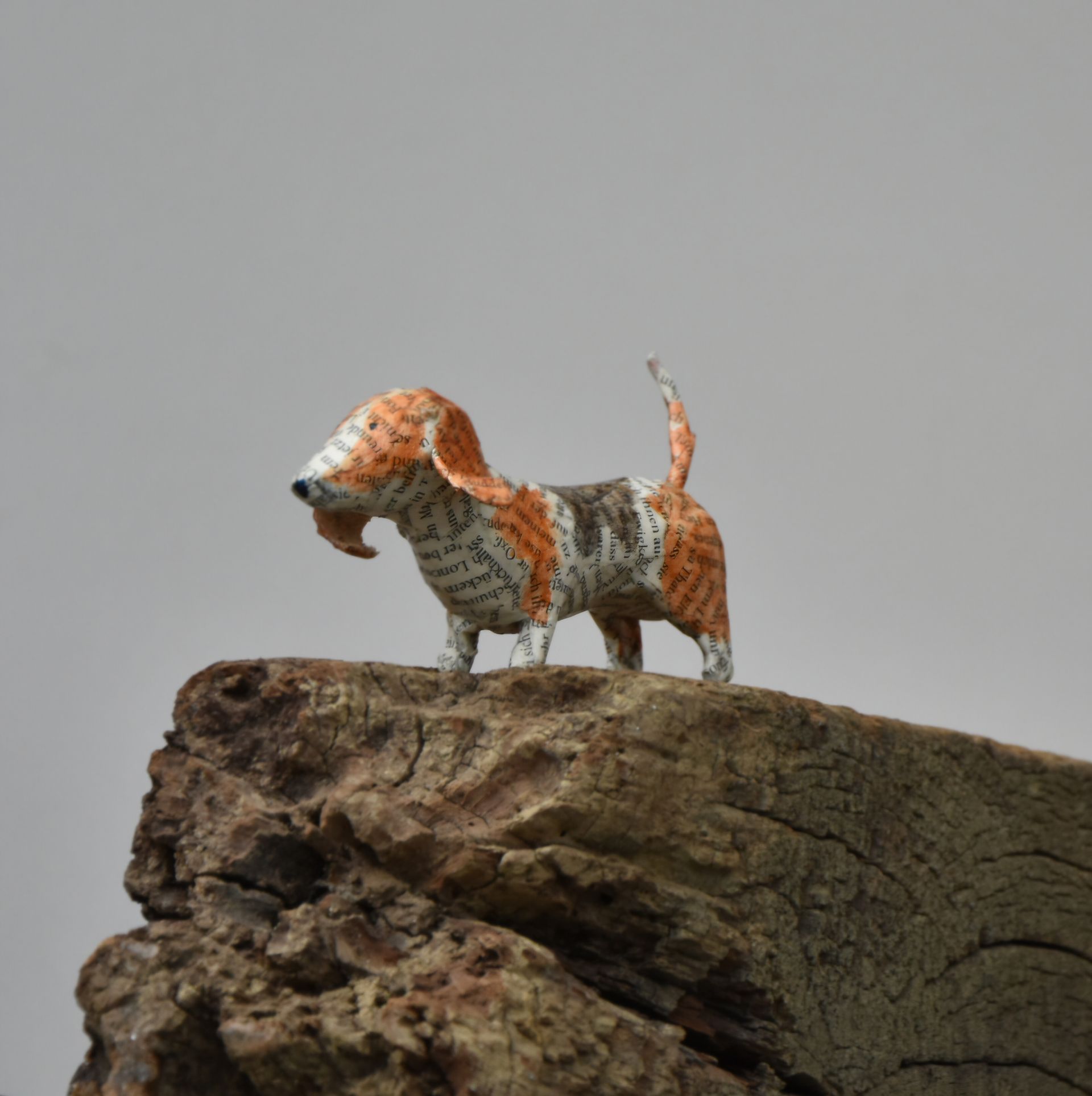 Een papieren basset hond staat bovenop een houten balk