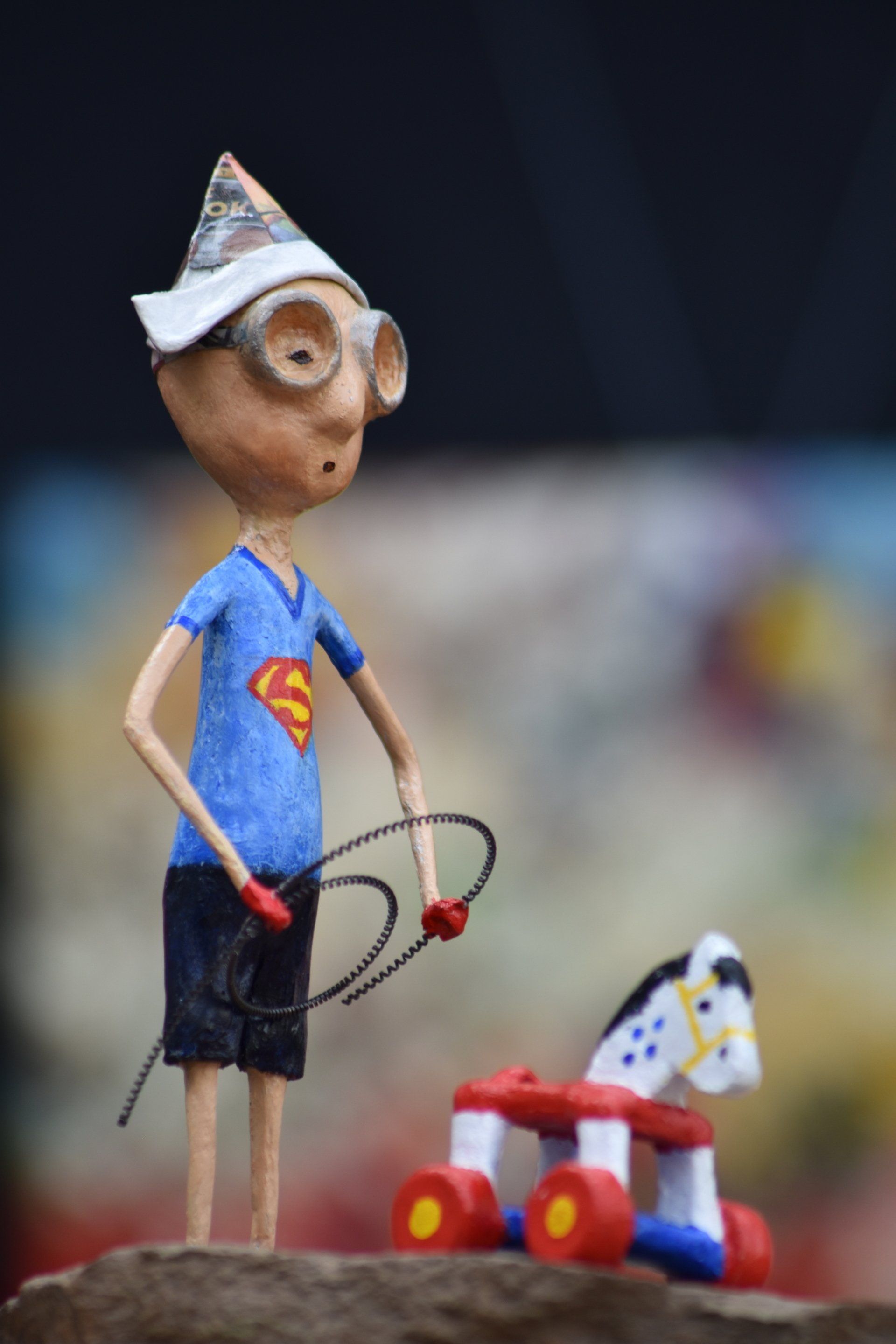 Een beeldje van een jongen in een Superman-shirt die een zweep en een speelgoedpaard vasthoudt