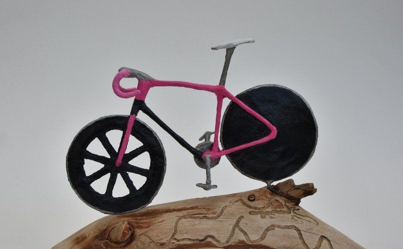 Een roze fiets staat bovenop een stuk hout