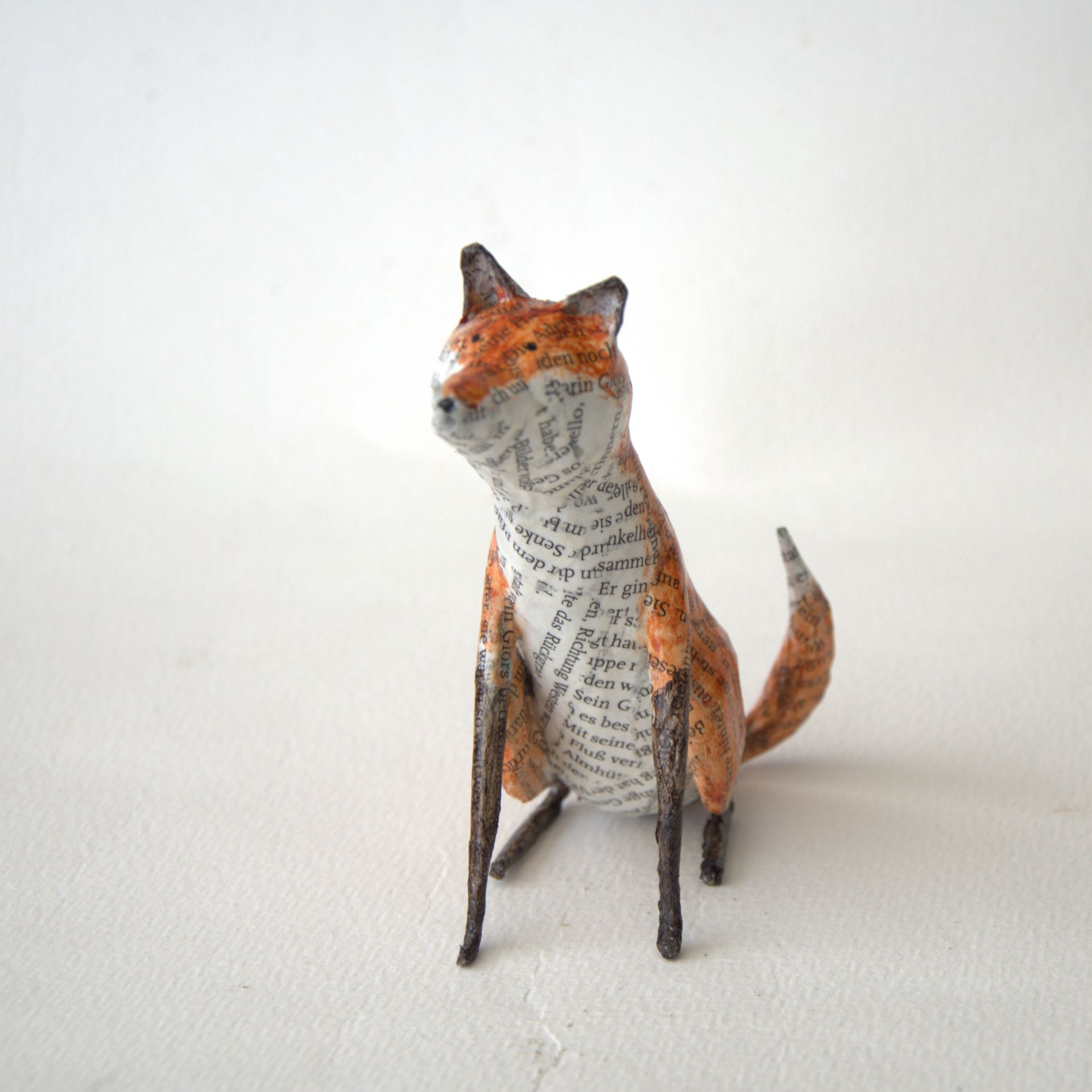 Een beeldje van een vos zit op een wit oppervlak