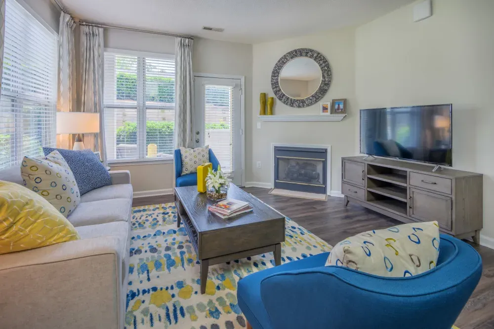 A living room with a couch , chair , coffee table , television and fireplace  at 23Hundred Ridgeview.