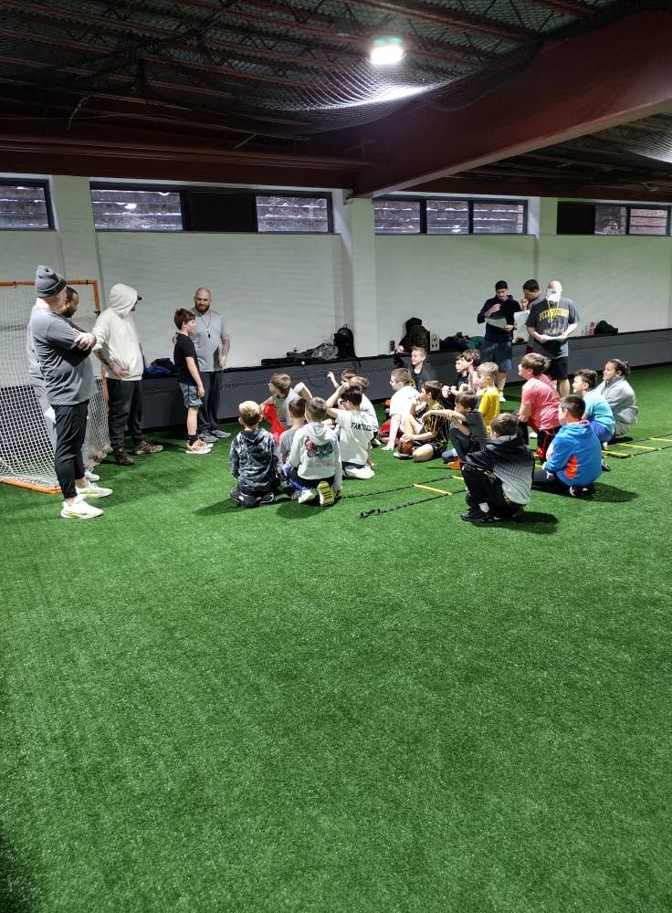 A group of children are sitting on the grass in a gym.