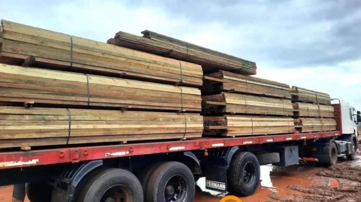 Camión cargado con pilas de tablones de madera, al aire libre.