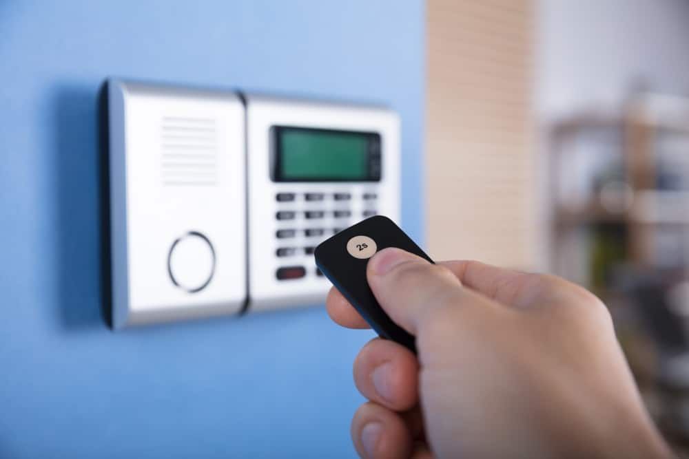 A Person Is Holding A Remote Control In Front Of A Security System — Eddie Williams Locksmiths in Cairns City, QLD