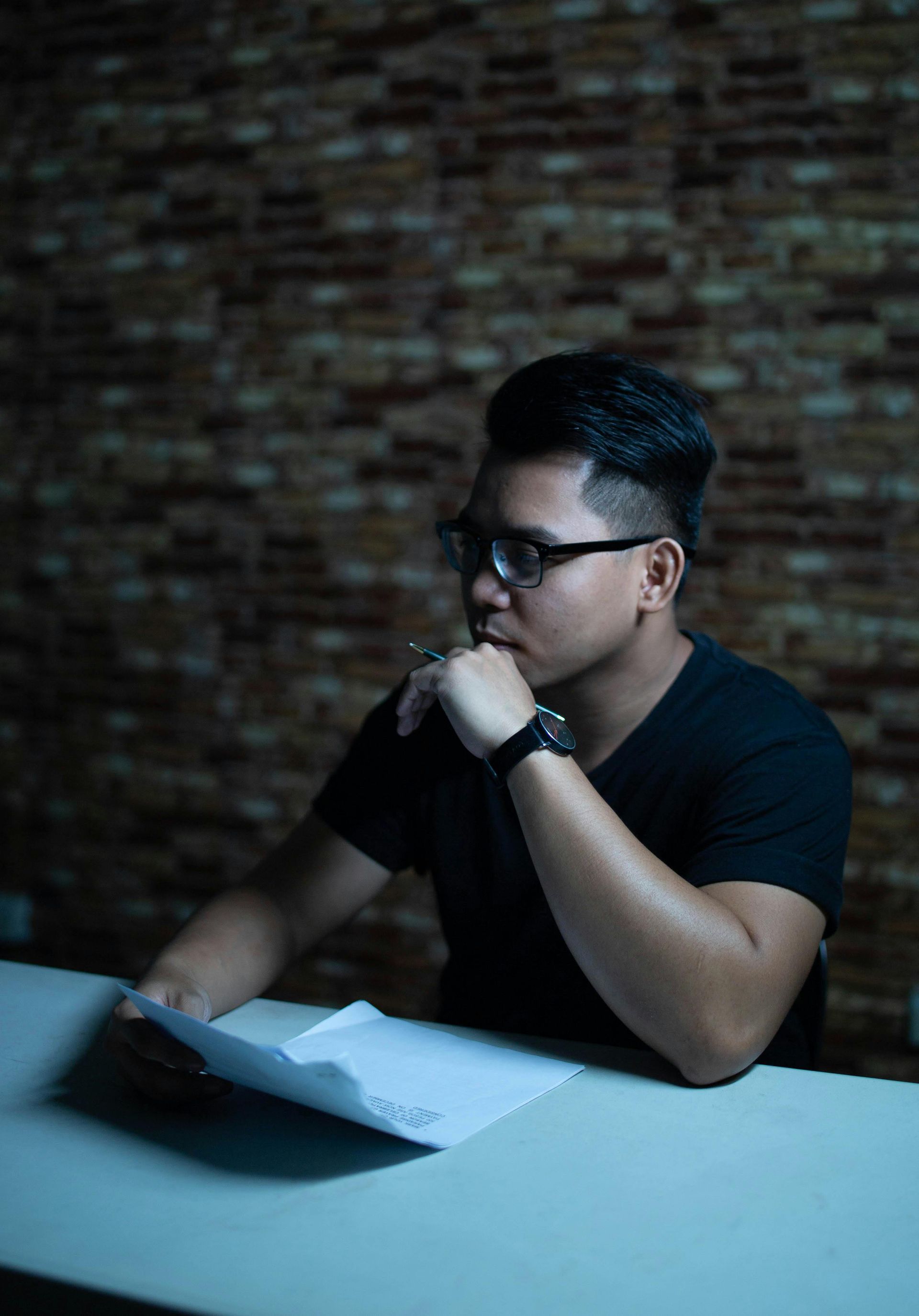 A man with a beard and glasses is thinking about something.