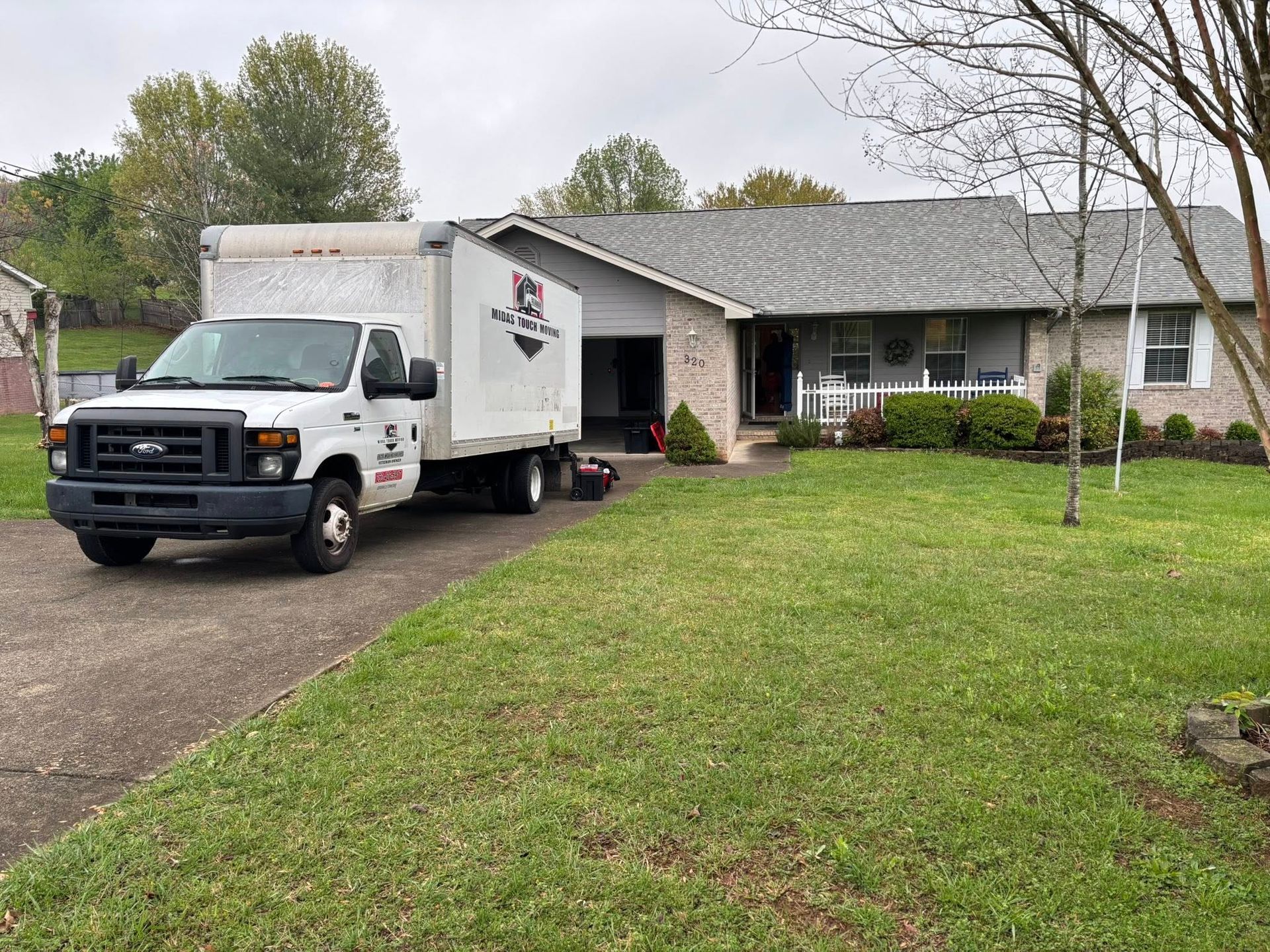White moving truck parked in front of a house, possibly unloading or loading belongings.