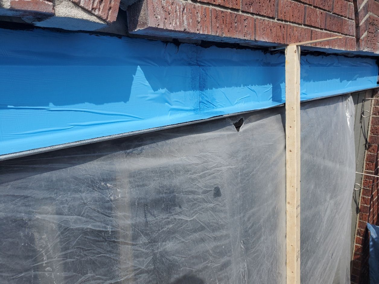 Un mur de briques avec un morceau de ruban adhésif bleu dessus.